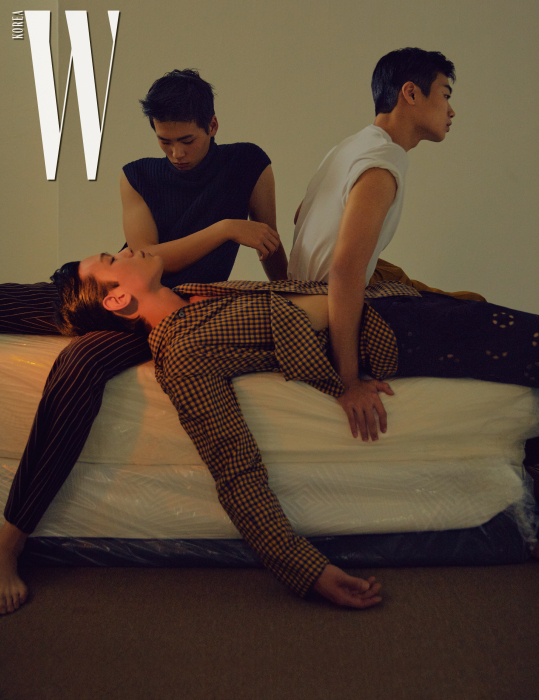 김진곤이 입은 네이비색 터틀넥 니트 베스트는 Dries Van Noten by Boon the Shop, 갈색 줄무늬 팬츠는 Acne Studios 제품. 임지섭이 입은 흰색 티셔츠는 Saint Laurent, 팬츠는 Kimseoryong, 은색 목걸이는 Kantique 1/4 제품. 노신신이 입은 체크 무늬 재킷은 Wooyoungmi, 펀칭 팬츠는 Dries Van Noten 제품.