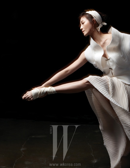 스커트로 연출한 옅은 베이지색의 플리츠 드레스는 Andy & Debb,건축적인 율동감이 느껴지는흰색 베스트는 Giorgio Armani 제품.