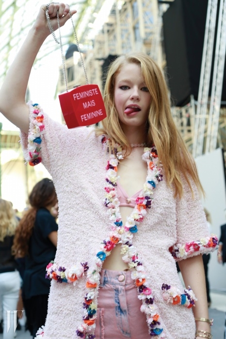 ‘페미니스트지만 페미닌하다’라는 문구의 샤넬 클러치를 든 모델 홀리 매이 사커의 귀여운 포즈.