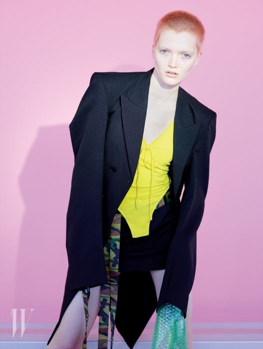 노란색 보디슈트와 검은색 스커트, 재킷은 모두 Vetements 제품. 카무플라주 벨트는 스타일리스트 소장품. Beauty note: Joico의 피어리 코럴 제품으로 머리카락을 밝게 물들였다.