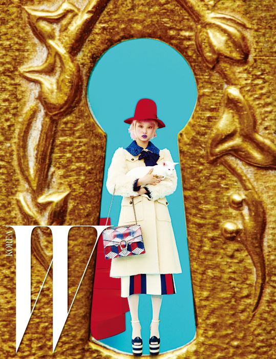 위트 있는 형태의 붉은색 펠트 모자, 보 장식의 푸른색 칼라를 더한 순백의 코트, 줄무늬 스커트, 크림색 타이츠, 플랫폼 샌들, 진주 장식 반지, 그리고 큐브 프린트의 디오니서스(Dionysus) 백은 모두 Gucci 제품.