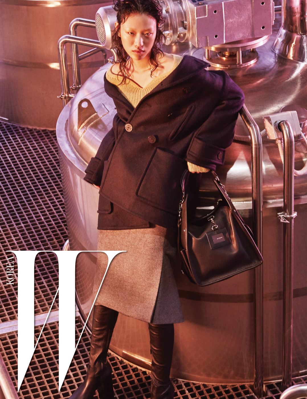 남색 스윙 피 코트, 베이지색 하트넥 니트 톱, 모직 소재의 회색 킥 스커트, 검정 플랫폼 사이하이 부츠, 검은색 툴 숄더백은 모두 Balenciaga 제품.