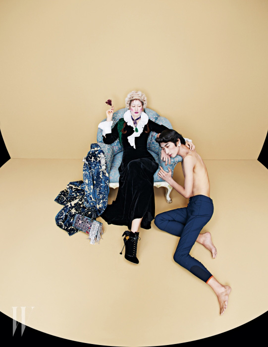 박세라가 착용한 주름 장식의 네크라인이 돋보이는 검정 벨벳 롱 드레스는 Ralph Lauren Collection, 신비로운 빛깔의 대담한 원석 장식 목걸이와 어깨 위에 연출한 초록빛의 깃털 장식 초커는 Dries van Noten, 반지와 팔찌가 이어진 금빛 핑거(슬레이브) 브레이슬릿은 Begadis by 10 Corso Como, 손에 든 깃털 장식 클립(브로치)은 Christopher Kane by My Boon, 앤티크한 디자인의 귀고리는 Modgone 제품. 소파 팔걸이에 연출한 화려한 주얼 장식의 브로케이드 문양 벨벳 코트와 벨벳 소재의 레이스업 슈즈는 Miu Miu, 바닥에 놓은 섬세한 비즈와 원석, 메탈릭한 프린지 장식의 백은 Dior 제품. 이봄찬이 착용한 승마 팬츠는 Hermes, 날개 모티프의 스트라스 엠브로이더리 클립 귀고리는 Saint Laurent 제품.