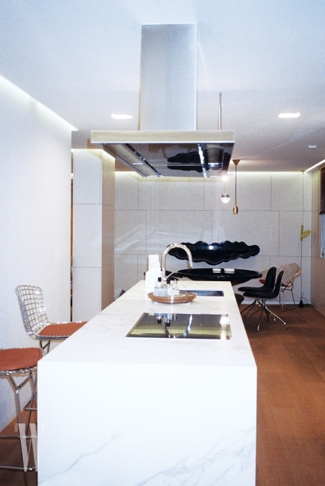 군더더기 없는 흰색과 스틸, 나무 바닥이 어우러진 주방과 다이닝 공간.