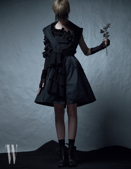 입체적으로 꽃잎을 장식한 원숄더 드레스는 21 Defaye, 베스트 재킷은 Prada, 허리에 묶은 스웨터는 Michael Michael Kors, 검은색 신발은 Celine 제품.