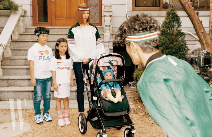 오빠가 착용한 츕파춥스 프린트 티셔츠는 Fila Kids, 줄무늬 헤드밴드는 Flakkiki, 운동화는 Prospecs Kids 제품 . 언니가 착용한 티셔츠와 스커트는 Fila Kids, 운동화는 Prospecs Kids 제품. 엄마가 착용한 아노락 점퍼는 Lacoste Collection, 피케 셔츠와 데님 진은 Lacoste, 줄무늬 헤드밴드는 The Studio K 제품 . 유모차는 Bugaboo 제품. 아빠가 착용한 초록색 점퍼는 Alexander Wang, 헤드밴드는 The Studio K 제품 .