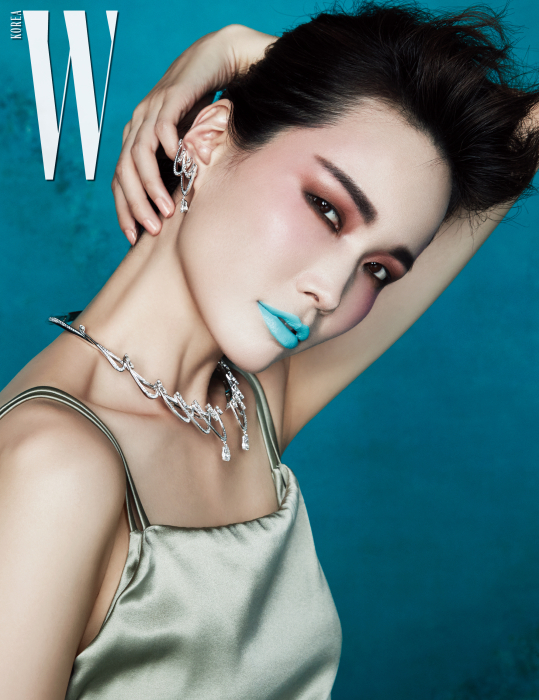 리츠 파리 호텔의 화려한 샹들리에를 연상시키는 우아한 곡선미가 돋보이는 브릴리언트 컷 다이아몬드 세팅의 목걸이와 귀고리는 Tasaki 제품. 은은한 광택의 새틴 톱은 COS 제품.