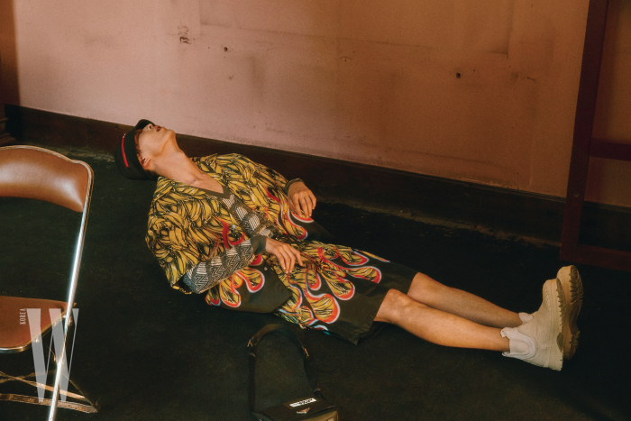 바나나 프린트 셔츠, 쇼츠, 니트 톱, 모자, 부츠, 가방은 모두 Prada 제품.