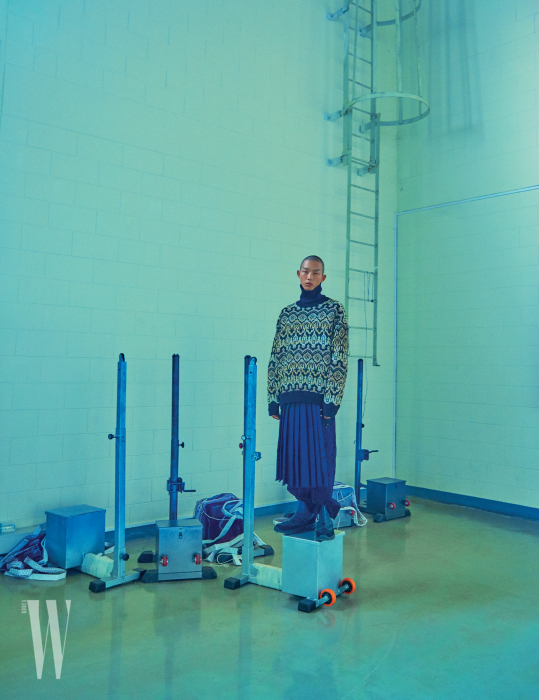 금사와 은사가 섞인 터틀넥과 검은색 아일릿 팬츠, 주름 스커트는 Dries Van Noten by Boon the Shop, 앵클부츠는 Prada 제품.