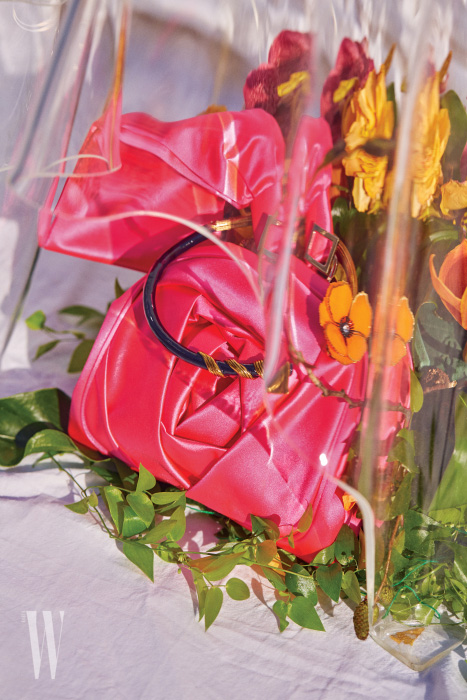 장미에서 영감을 받은 새틴 소재의 로즈 브레이슬릿 소프트 클러치는 Roger Vivier, 입체적인 꽃 장식의 메탈 초커는 Fendi 제품.